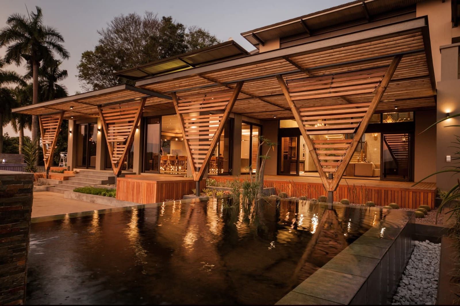 House and pond at dusk with exterior lighting